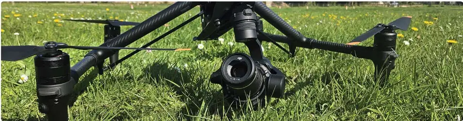 Drone DJI Inspire posé dans l’herbe, caméra Zenmuse au premier plan