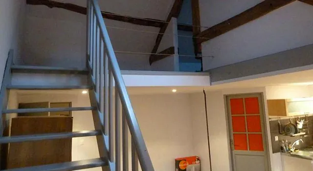 Escalier à rampe métallique menant à la chambre à l’étage, cuisine équipée en arrière-plan