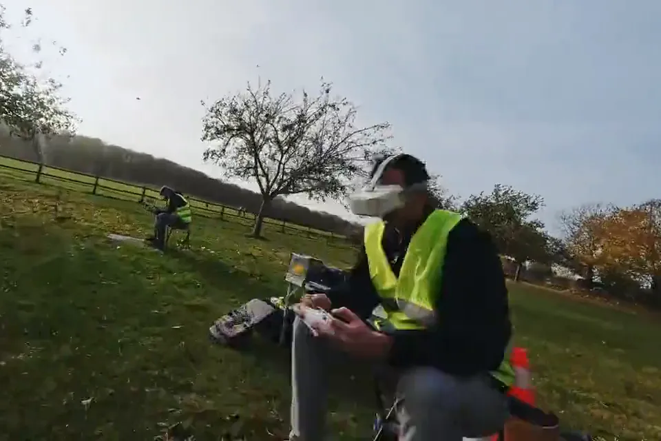 Terrain extérieur du campus : un pilote en gilet jaune, masque FPV sur les yeux, radiocommande en main